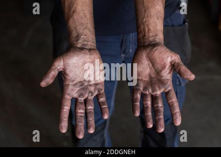 High angle of crop unrecognizable male mechanic showing dirty hands while working in repair service workshop Stock Photo