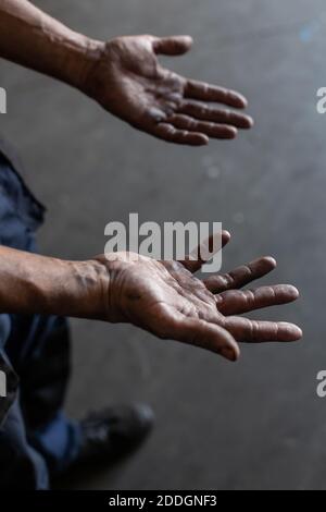 High angle of crop unrecognizable male mechanic showing dirty hands while working in repair service workshop Stock Photo