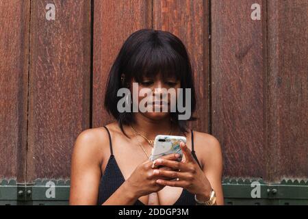 Young African American female wearing black top with decollete texting on smartphone Stock Photo