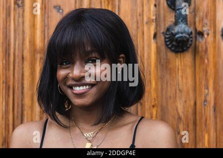 Delighted African American female standing against wooden wall Stock Photo