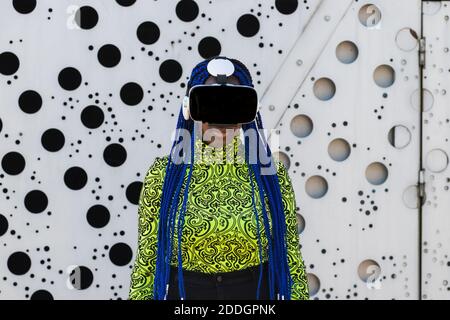 African American female with blue hair standing in street in VR goggles while experiencing virtual reality Stock Photo