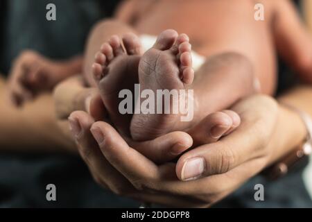 Closeup crop unrecognizable Woman holding tiny feet of anonymous baby Stock Photo