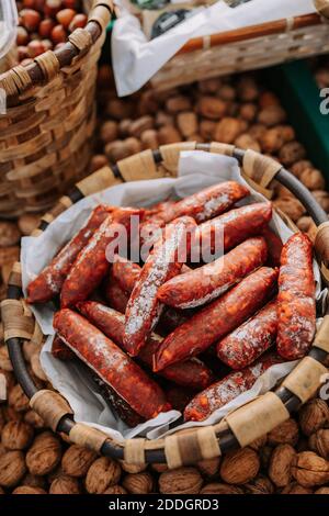 From above of whicker basket with yummy appetizing chorizo sausages placed among containers with nuts on local agricultural market Stock Photo