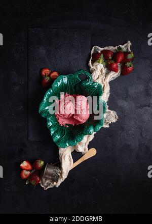 Top view of scoops of tasty ice cream in plate placed on table with fresh strawberries and napkin Stock Photo