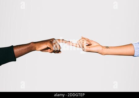 Close-up of a black man' touching white Woman's finger over white background Stock Photo