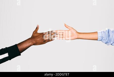 Close-up of a black man's hand holding a white Woman's hand over white background Stock Photo
