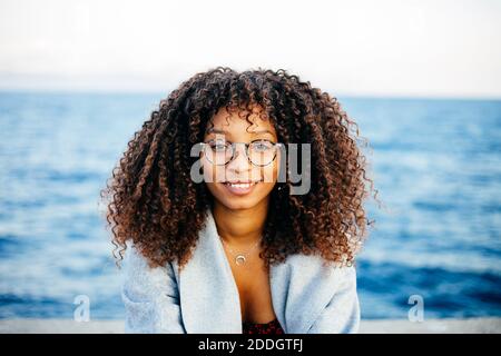 Young smiling red haired female in casual clothes wearing VR headset while enjoying virtual reality experience in living room at home Stock Photo