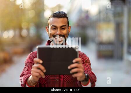 Young man using digital tablet outdoors at urban setting Stock Photo