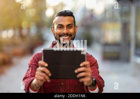 Young man using digital tablet outdoors at urban setting Stock Photo