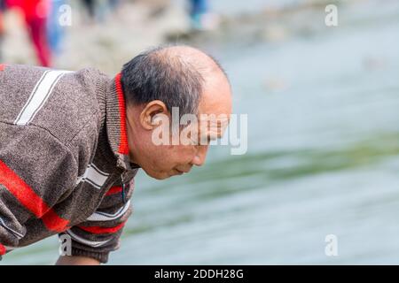 A Chinese old man finding fish at the river at the Shenzhen Bay of China during weekend Stock Photo