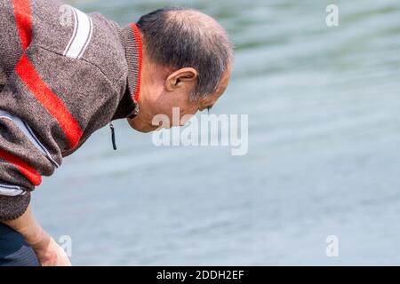 A Chinese old man finding fish at the river at the Shenzhen Bay of China during weekend Stock Photo