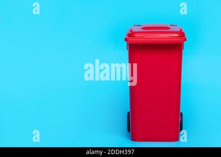 red wheelie waste bin on blue background. Stock Photo