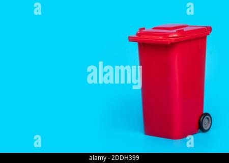 red wheelie waste bin on blue background. Stock Photo