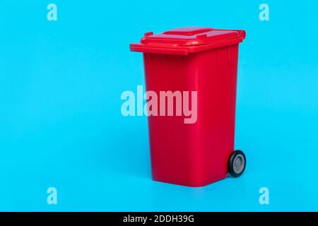 red wheelie waste bin on blue background. Stock Photo
