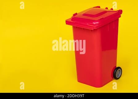 red wheelie waste bin on yellow background. Stock Photo