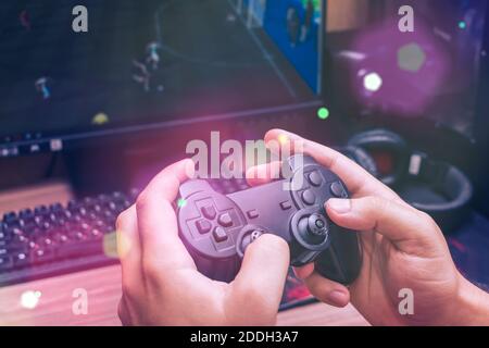 Man holds a game joystick in his hands while playing a video game Stock Photo