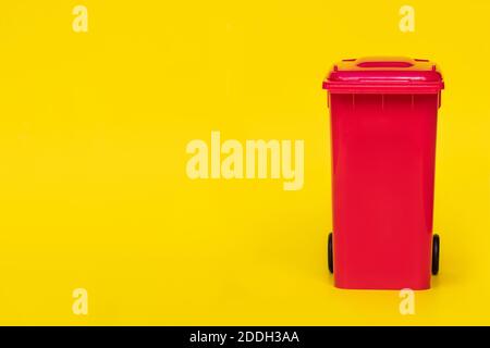 red wheelie waste bin on yellow background. Stock Photo