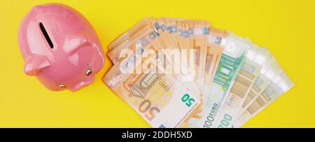 top view of stack of euro bills and piggy bank on yellow background, saving money and finance concept Stock Photo