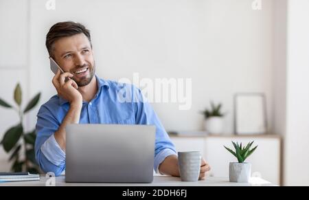 Handsome Male Entrepreneur Having Phone Conversation And Drinking Coffee At Workplace Stock Photo