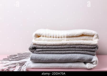 A stack of folded textiles - blankets and towels on the background light walls. Stock Photo