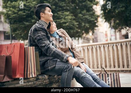 young asian couple resting relaxing outdoors while shopping in the city Stock Photo
