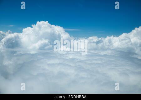 An aerial shot of white fluffy cumulus clouds from above with a blue sky in the background Stock Photo