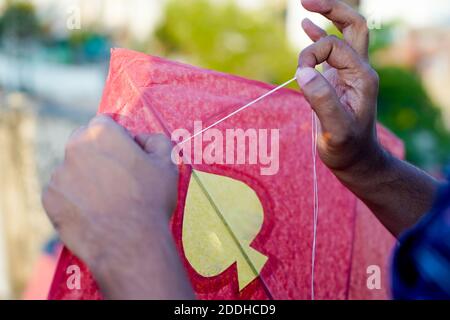 Man threading a paper and wood kite in order to fly it on the indian harvest festival of makar sankranti or uttarayana Stock Photo