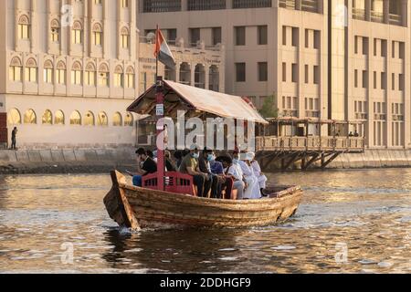 Dubai, UAE - September 1 2020: Local people wearing a face mask due to Covid Pandemia travel on an Abra, the traditional wooden ferry  on the Creek in Stock Photo
