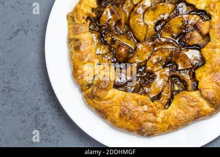 Rustic apple tart with cinnamon apricot jelly glaze and sugared shortcrust on white plate with copy space - top view close up image Stock Photo