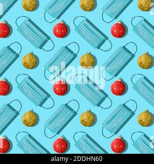 Trendy seamless Christmas pattern made of Christmas tree ball and a protective mask from the virus on blue background. Minimal concept of the new year Stock Photo