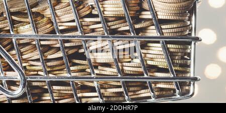 Close up picture of golden coins in a miniature shopping cart, color toned conceptual picture, selective focus. Stock Photo