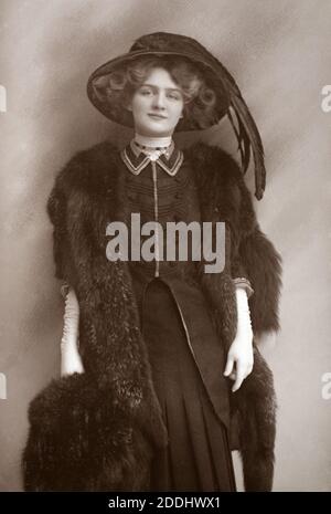 The notable Edwardian English actress and singer Lily Elsie (1886 – 1962) wearing a black hat, dress,and furs, taken from a photographic postcard from the era. Stock Photo