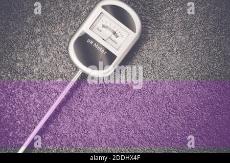 A top view closeup of an analog tool to measure soil ph on a rough textured background Stock Photo