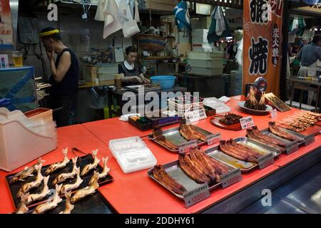 Horizontal view of one of the Omicho fresh food market convenience fish stalls with the fishmongers making brochettes in the background, Kanazawa Stock Photo