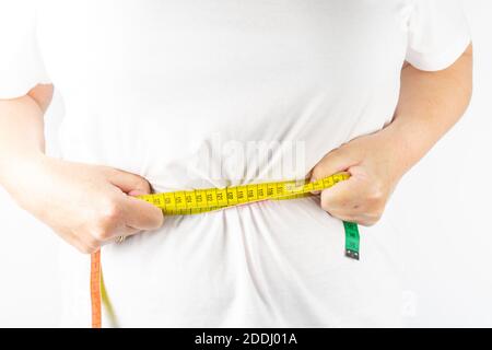A closeup shot of a female holding a measuring tape around her waist Stock Photo