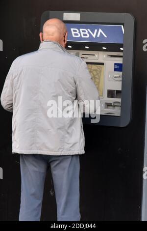 A man withdraws money from a BBVA Bank ATM in a bank office in Vendrell Tarragona.The merging of BBVA (Bank Bilbao Vizcaya Argentaria) and Sabadell Bank would create the second banking giant of almost 600,000 million in the Spanish market by volume of assets, only behind the entity that resulted from the merging of CaixaBank and Bankia. Stock Photo