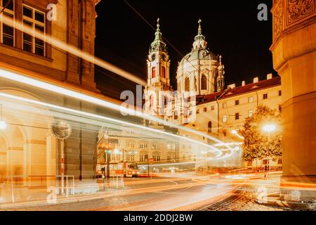 Night view of St. Nicolas Church, Prague, Czech republic. Long exposure city lights.Motion speed scene.Traffic trails in town.City street at night. Stock Photo