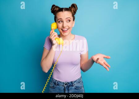 Photo of pretty charming lady two funny buns hold cable telephone handset speaking chatting friends discussing fresh gossips rumors wear casual purple Stock Photo