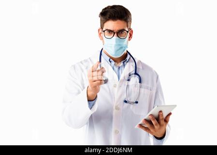 Shot of a male doctor wearing face mask and pointing his finger to you while standing at isolated white background. Stock Photo
