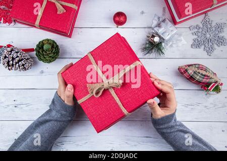 Christmas background. Gift boxes with colorful shiny Christmas decorations on the whiteboard, and the girl is holding the new year gift box. Stock Photo