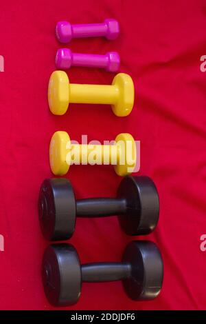 Colorful dumbbells on red background Stock Photo