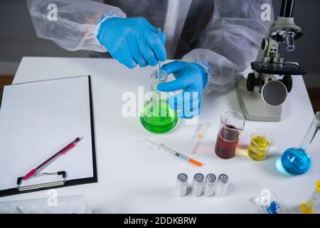 Scientist shaking green fluid in beaker. Young laboratory assistant making test or research in lab. Technician testing chemistry lab experiment and Stock Photo