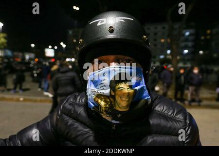 Naples, Italy. 25th Nov, 2020. A man wears the mask depicting Maradona outside the San Paolo stadium in Naples to pay homage to the great champion of football history Diego Armando Maradona on the day of his death with choirs, banners and flags. Credit: Independent Photo Agency/Alamy Live News Stock Photo