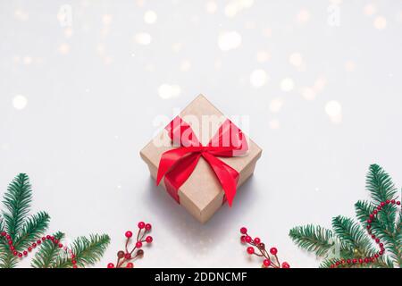 Vintage craft gift box with red ribbon as presenf for Christmas, New year on white background with fir tree branch, garland and lights. Flat lay Stock Photo