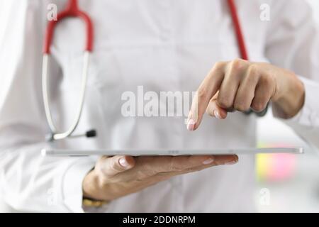 Doctor holding tablet in his hands and pointing at it with his finger closeup Stock Photo