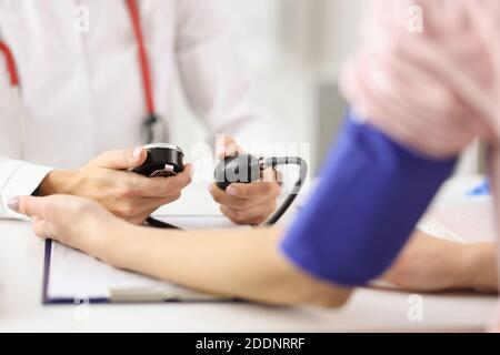 Doctor cardiologist measuring blood pressure of patient with tonometer in clinic Stock Photo