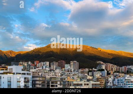 Cityscape and aerial view with skyscrapers of the modern Quito city at sunrise with Pichincha volcano, capital of Ecuador in the Andes mountains. Stock Photo