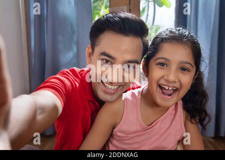 Father and daughter enjoying at home Taking selfies with smart phone Stock Photo