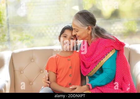 Grand mother holds her grand daughter as the grand daughter looks in to the camera Stock Photo