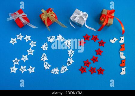 Creative christmas card with 2021 number made of merry decorations and colorful gifts on blue background. Creative concept of the new year. Copy space Stock Photo